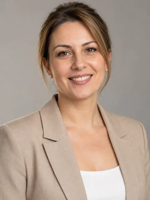 Portret al Carmenei Tudose, cu sacou bej și cercei cu perle, pe fundal gri